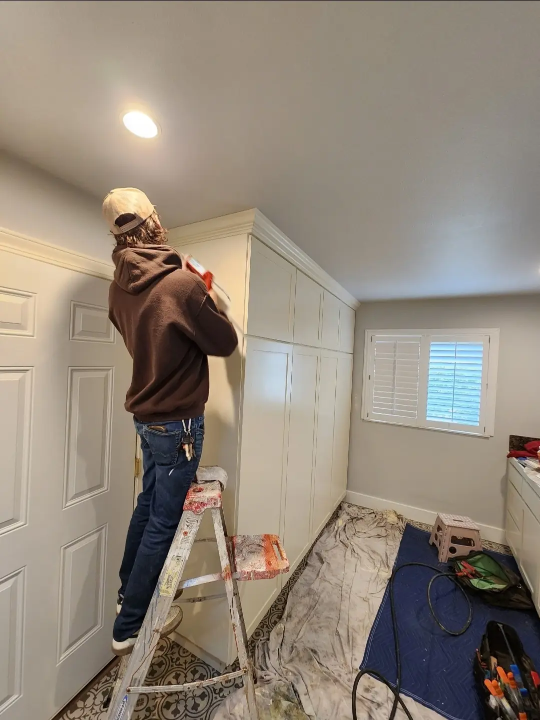 Justin completing crown molding and caulking details on cabinetry